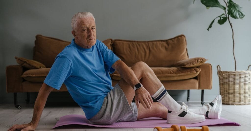 Elderly man enjoys a healthy lifestyle by exercising indoors on a yoga mat with weights.