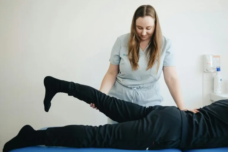 A StretchMasters physiotherapist helps a patient stretch their leg during a therapy session