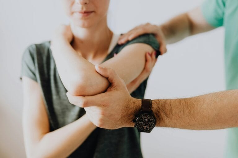 A StretchMasters therapist provides assisted stretching to a patient's arm in a clinic setting, focusing on health and care.
