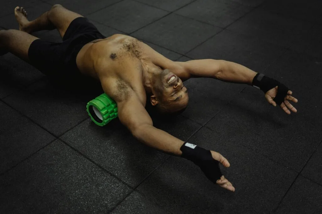 Athlete exercising with a foam roller in a fitness center.