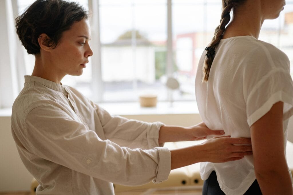A StretchMasters physiotherapist performs a back alignment therapy on a patient indoors.