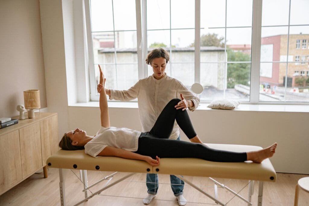 A specialist StretchMasters therapist performs therapy on a woman lying on a massage table in a modern clinic setting.
