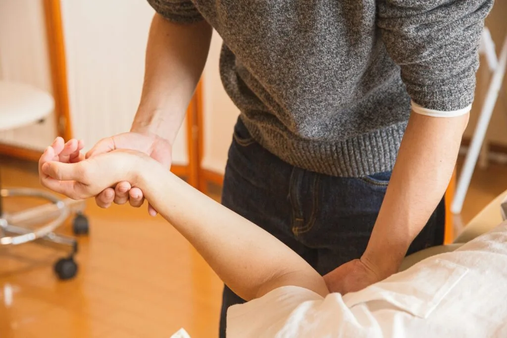 A StretchMasters® Therapist assisting a patient with wrist therapy. Focus on healthcare and wellness.
