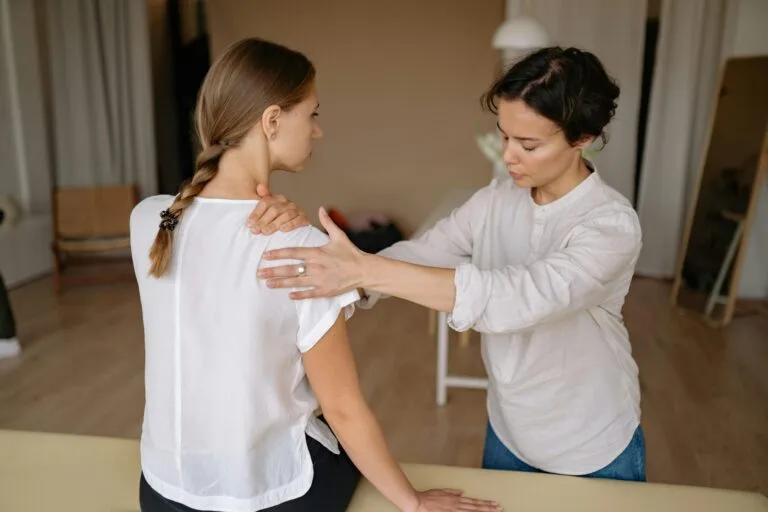 A therapist performing a shoulder stretch on a woman to relieve physical tension.