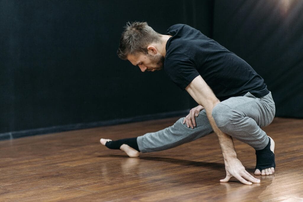 Mid-adult man stretching in a dance studio, emphasizing flexibility and balance.