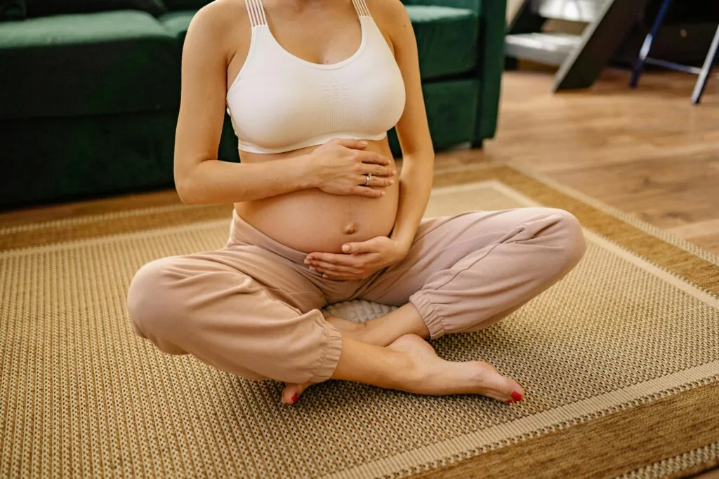 Expectant mother sitting in a serene setting practicing meditation and mindfulness indoors.